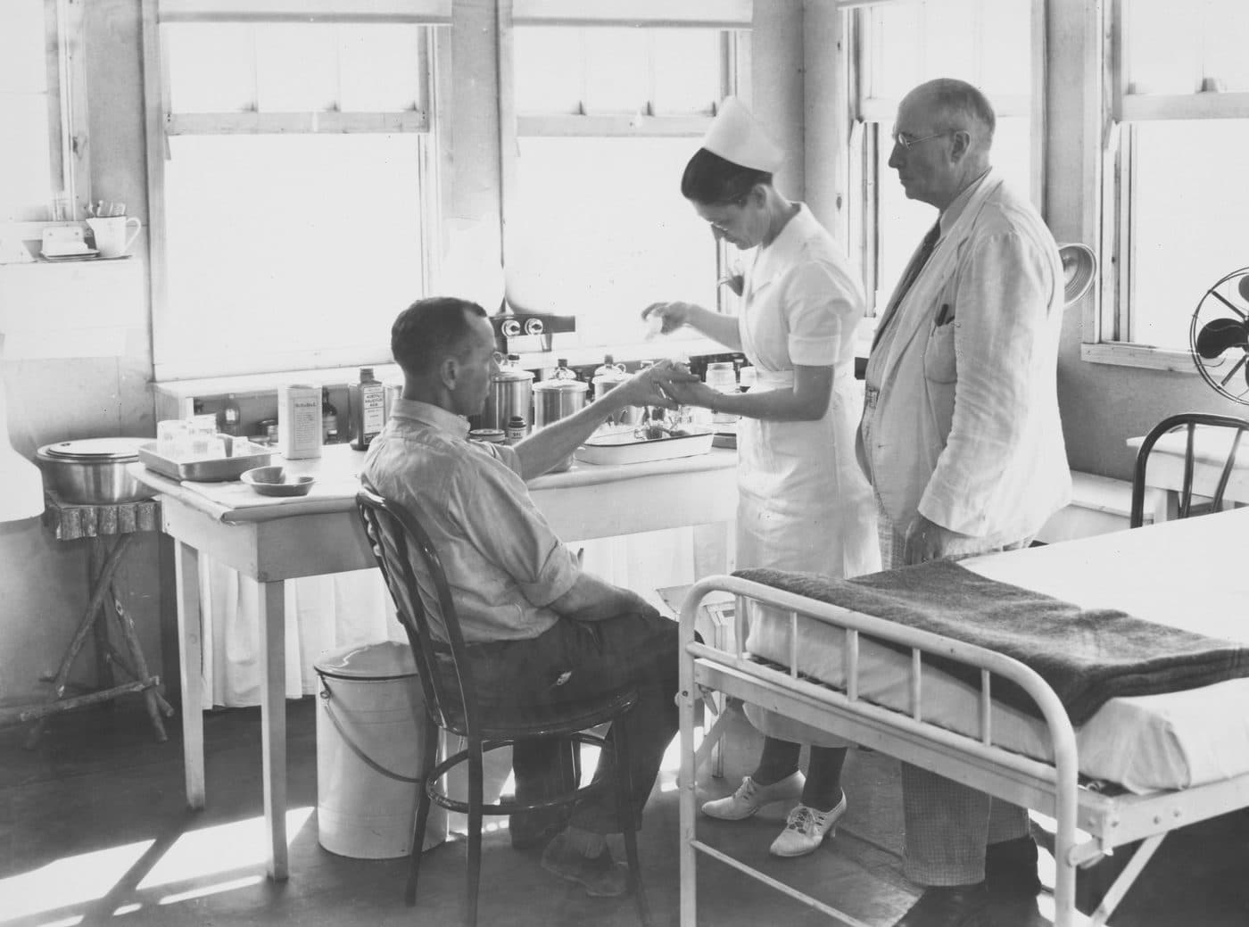 Historical photograph of a nurse attending a patient while a doctor observes